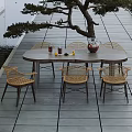 Outdoor Table with Rattan Chairs Vase Drinks and Lemon Slices on Wooden Deck by Water