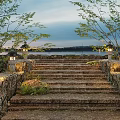 Stone Steps Landscape with Stone Walls Illuminated Lanterns and Greenery by Water at Twilight