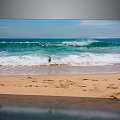 Scenic Sandy Beach With Rolling Ocean Waves Footprints And People Enjoying Shallow Water