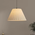 Pleated Cream Pendant Light Hanging In Interior With Light Gray Wall And Green Plant
