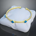 Elegant Gold Textured Bracelet With Blue Gemstones On White Display Cushion