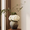 Gray Ceramic Vase Holding White Hydrangeas And Green Branches Against White Wall With Curtain
