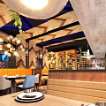 Modern Restaurant Interior Design With Wooden Ceiling Blue Accents Large Screens And Decorative Plants