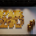 Yellow Wooden Panel Art Installation With Landscape Patterns And Small House Structures In Indoor Lighting