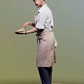 Woman in Brown Apron with Bow Holding Spatula Preparing Meal in Kitchen