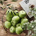 Ceramic Bowl Filled With Fresh Green Apples And Olive Branches Along With Walnuts On Wooden Table