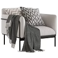 Light Gray Armchair With Chevron Pattern Pillows And Gray Blanket On Black Metal Legs