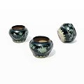 Three Black Ceramic Jars With Green Vine Patterns On White Background