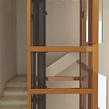 Modern Elevator with Glass Door and Brass Frame in Interior Space Alongside Staircase