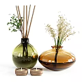 Glass Vases In Green And Amber Holding Small White Flowers Green Foliage And Small Candles