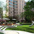 Modern Residential Landscape with High Rise Buildings Lush Trees Lawn and Leisure Seating Areas