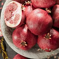 Rustic Ceramic Bowl Filled With Fresh Pomegranates Sliced Sections And Natural Decorative Branches