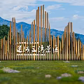 Scenic Wall With Wooden Mountain Shaped Vertical Slats Against Blue Sky Mountain Backdrop And Lawn