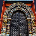 Intricately Carved Black Entrance Gate With Red Brick Walls And Colorful Decorations