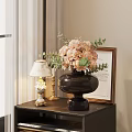 Dark Vase With Pink Flowers And Green Leaves On Dark Table With Lamp And Frame