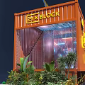 Orange Container Building Design With EN BLOC Sign Wooden Platform And Plants
