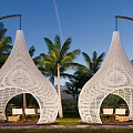 White Conical Woven Tents With Outdoor Seating Among Palm Trees And Mountain Backdrop