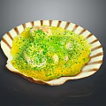 Creamy Yellow Savory Dish Served in Shell Shaped Plate Topped with Green Seasoning and White Chunks