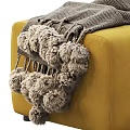Stylish Yellow and Green Ottoman with Gray Pom Pom Blanket and Brown Strap Detail