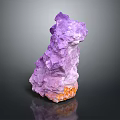 Purple Crystalline Mineral Specimen With Irregular Shape And Orange Base On Dark Reflective Surface