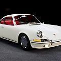 White Classic Porsche Sports Car With Red Interior Parked On Gray Floor Against Black Background