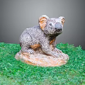 Koala Sculpture on Green Grass with Stone Base and Gray Orange Fur