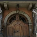 Residential Building Entrance Featuring Arched Wooden Doors Stone Statues And Classical Design