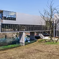 Modern Cultural Center Building With Large Glass Windows And Water Pool Reflection In Natural Surroundings