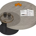 Round Light Gray Stone Coffee Table With Black Base Oranges Open Magazine And Glass Cups