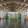 Warehouse Workspace With Green Metal Fence Cardboard Boxes High Ceiling And Workers