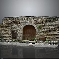 Ancient Stone Building Featuring Arched Wooden Door And Rough Stone Walls