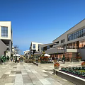 Modern Commercial Street With Stylish Buildings Stone-Paved Walkway Green Plants And Pedestrians