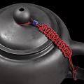 Black Tea Set with Red Tassel Decorated Teapot and Two Black Teacups Filled With Tea