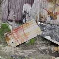 Broken Old Weathered Wooden Planks And Metal Sheets In Ash Debris With Overgrown Grass