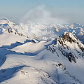 Snowy Mountain Peak With Snow Covered Slopes Rocky Outcrops Under Clear Blue Sky