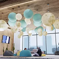 Modern Lounge Area With Pastel Spherical Pendant Lights Large Windows And People Relaxing