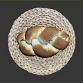 Freshly Baked Golden Brown Braided Bread On Woven Mat Ready For Serving