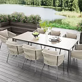 Outdoor Wicker Chairs With Wooden Table On Patio By Lake And Green Plants