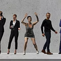 Group of People in Casual and Formal Attire Standing with Diverse Actions Against Gray Wall
