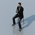 Man Sitting On Chair In Black Blazer Gray Shirt Dark Jeans And Black Sneakers