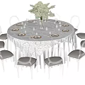 Elegant Round Dining Table Set With White Tablecloth Flower Vase And Cushioned Chairs