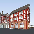 Red White Half Timbered Commercial Complex With Gabled Roofs Multi Story Retail Spaces And Greenery