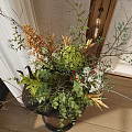 Decorative Black Vase With Green Plants Orange Blooms White Flowers And Twigs On Dark Table