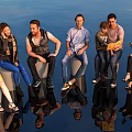 Diverse Group of People Sitting on Cylindrical Seats with Reflections on Shiny Black Floor
