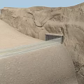 Scenic Desert Highway Leading To Tunnel Through Rocky Cliffs And Sand Dunes