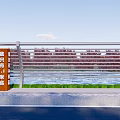 Modern Metal Fence With Horizontal Bars Along Waterfront Green Grass And Blue Sky