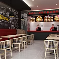 Modern Dessert Shop Interior With Red Uniform Staff Counter Tables Chairs And Green Plant Shelves