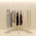 Curved Silver Metal Clothes Rack Displaying Dresses Tops and Garments with Beige Wall Background