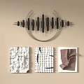 Black Metal Wall Hanging with Cylindrical Design and Silver Rings Above Textured White Brown Artworks