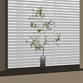 Dark Stone Vase with Slender Branches and Tiny Flowers on Windowsill Against White Blinds
